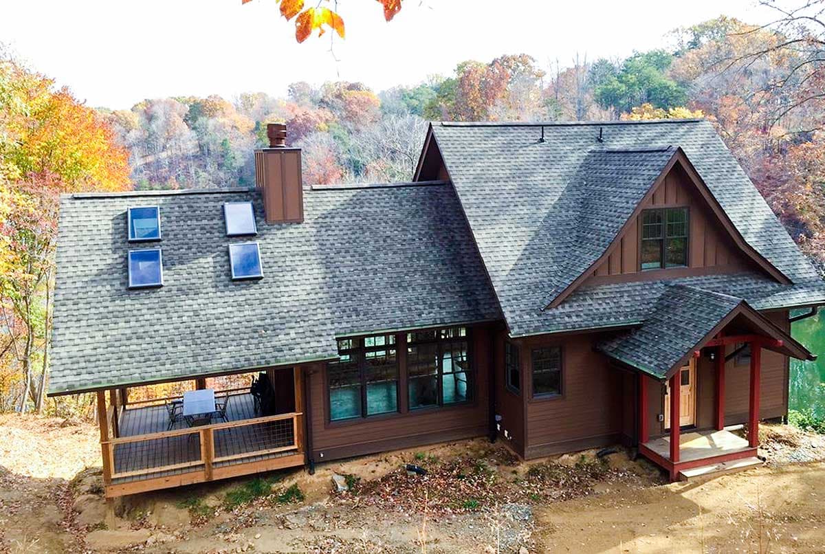 House plan exterior. Two-story with gable roof, dormers, and covered porch. Features include a chimney and exposed rafter tails.
