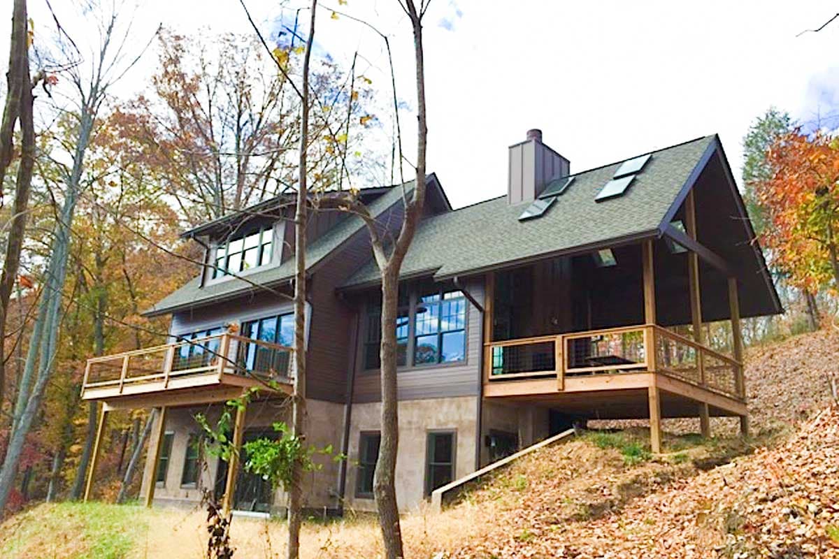 House plan exterior featuring a multi-story design with large windows, multiple decks, and a covered porch with a sloped roof.