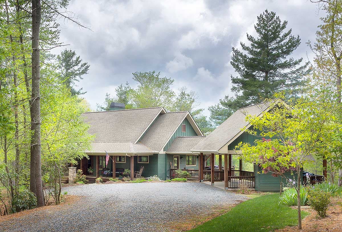 House plan exterior with a covered front porch, multiple gables, and an attached covered carport. Features a sloped roofline.