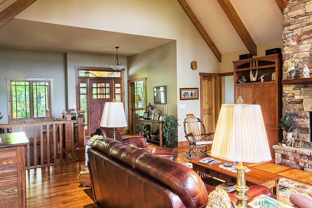 Interior view of a living room with vaulted ceiling, exposed beams, stone fireplace, and wood accents.