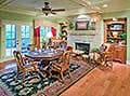 Dining area with round table near fireplace, built-in bookshelves, and French doors leading outside.