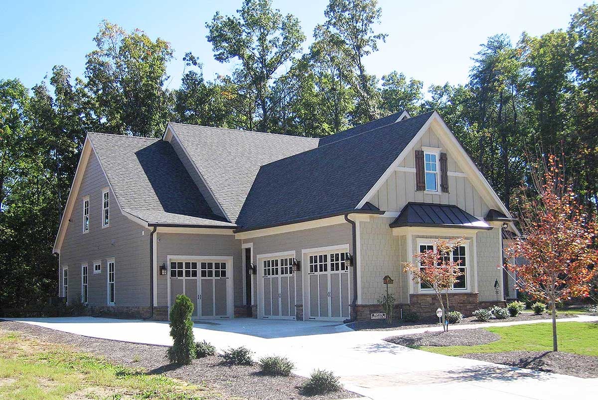House plan exterior: Modern Farmhouse style, two stories, with a three-car garage, gables, and a bay window.