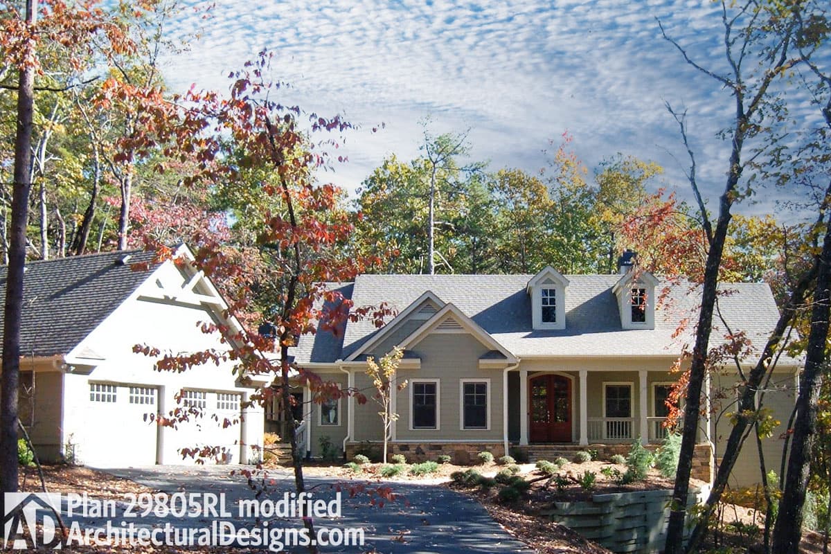 House plan exterior: Ranch style, one story with attached three-car garage, prominent gable, covered porch with columns, and dormer windows.