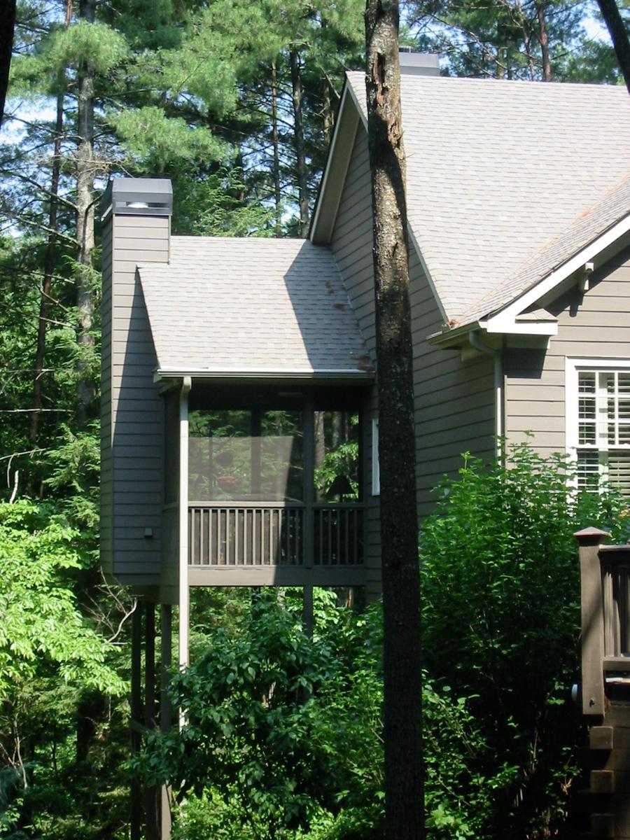 House plan exterior with screened porch elevated on stilts, a prominent chimney, and multiple gables.