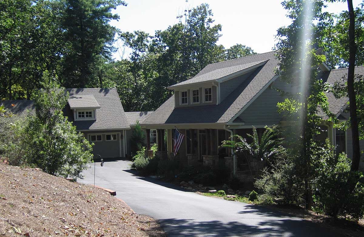 House plan exterior: Two-story home with gabled dormers, covered front porch with stone columns, and attached garage.