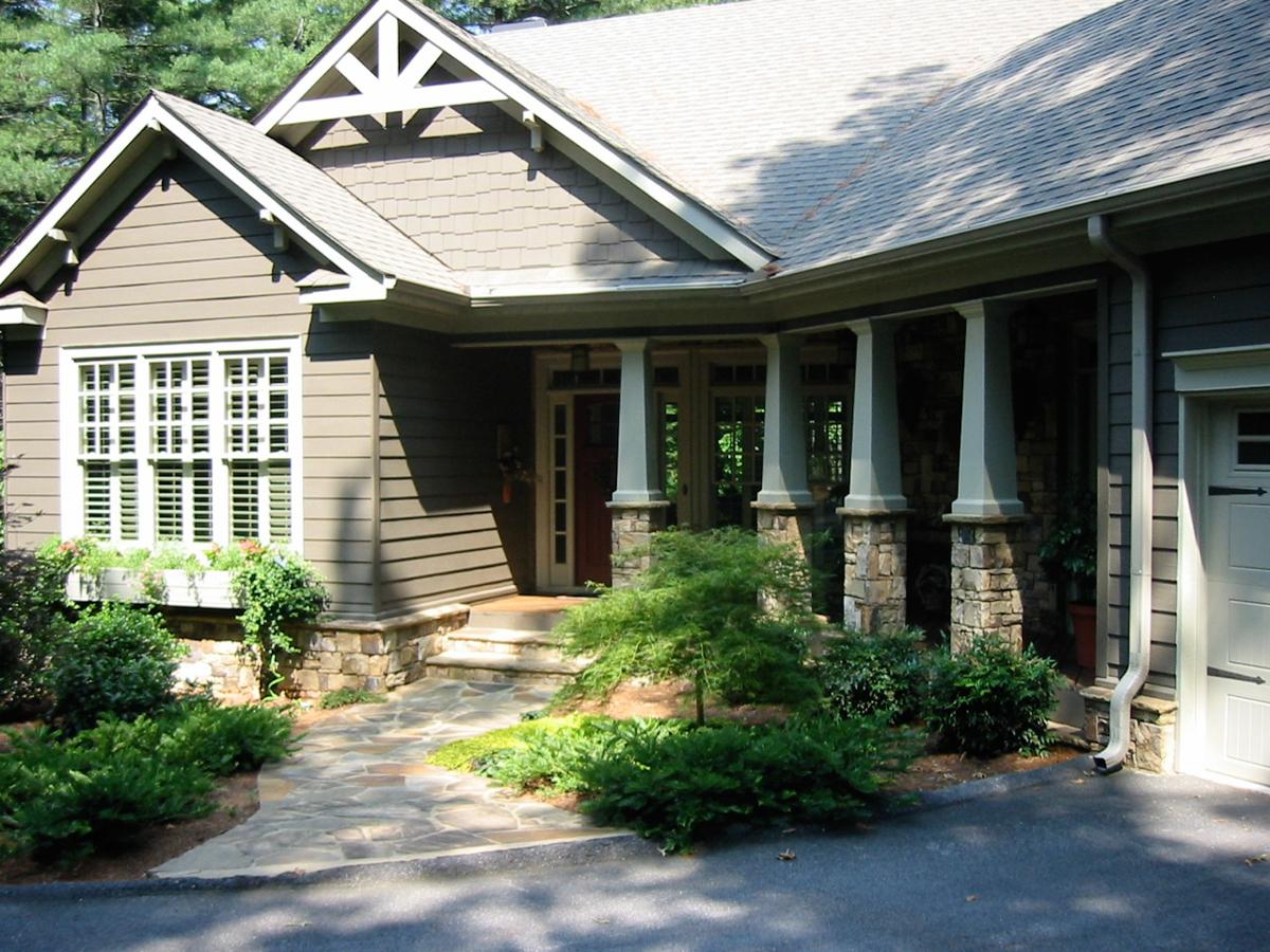 House plan exterior: Two-story modern farmhouse with stone column porch, gabled dormers, and multi-pane windows.