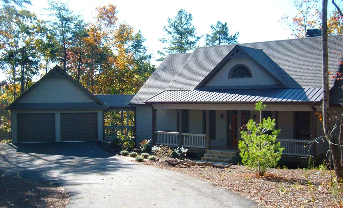 House plan exterior: Two-story home with attached two-car garage, covered front porch, gabled dormer, and metal roof.