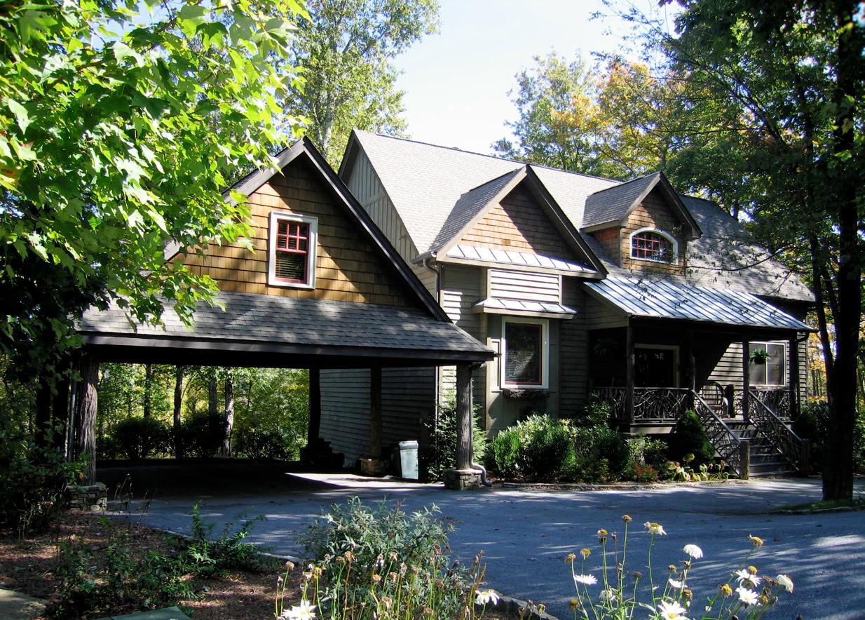 House plan exterior with prominent gables, dormers, wood shake siding, and an attached carport. 