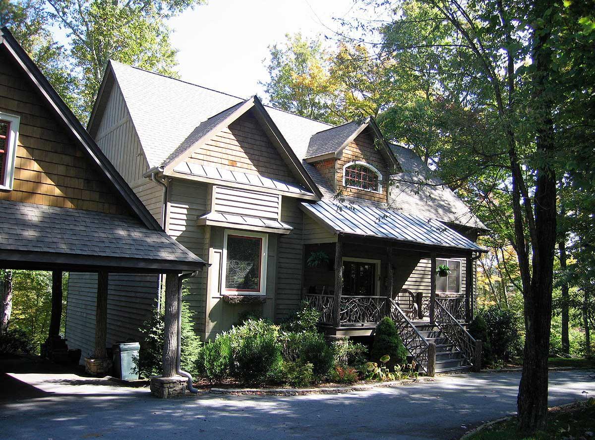 House plan exterior: Two-story structure with wood shingle siding, prominent gables, and a covered front porch with decorative railing.