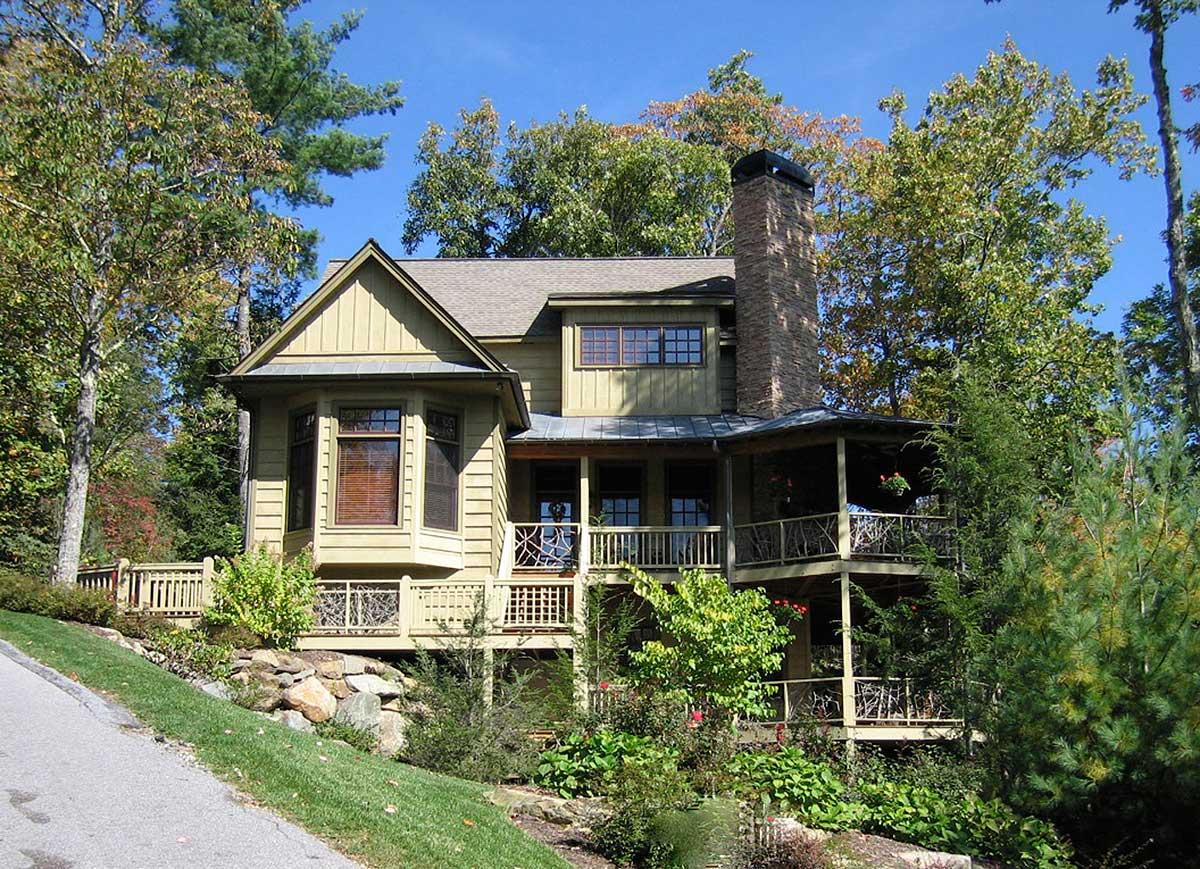 House plan exterior: Two-story home with bay window, gabled dormer, stone chimney, and multi-level porches.