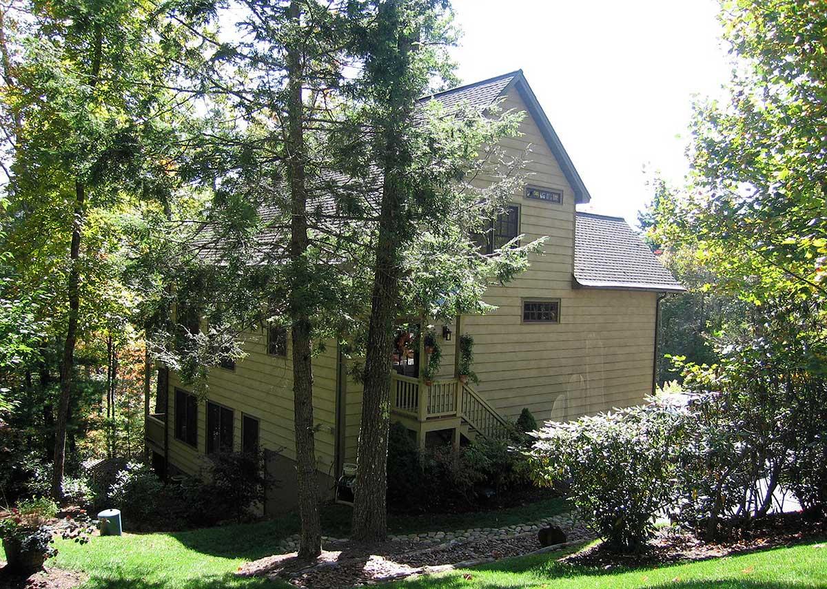 House plan exterior: Two-story home with gabled roof, siding, and a prominent front staircase with railing.