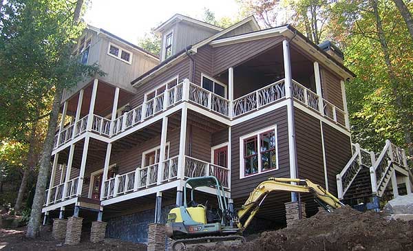 House plan exterior: Multi-story home with multiple wraparound porches, unique branch railings, and dormer.