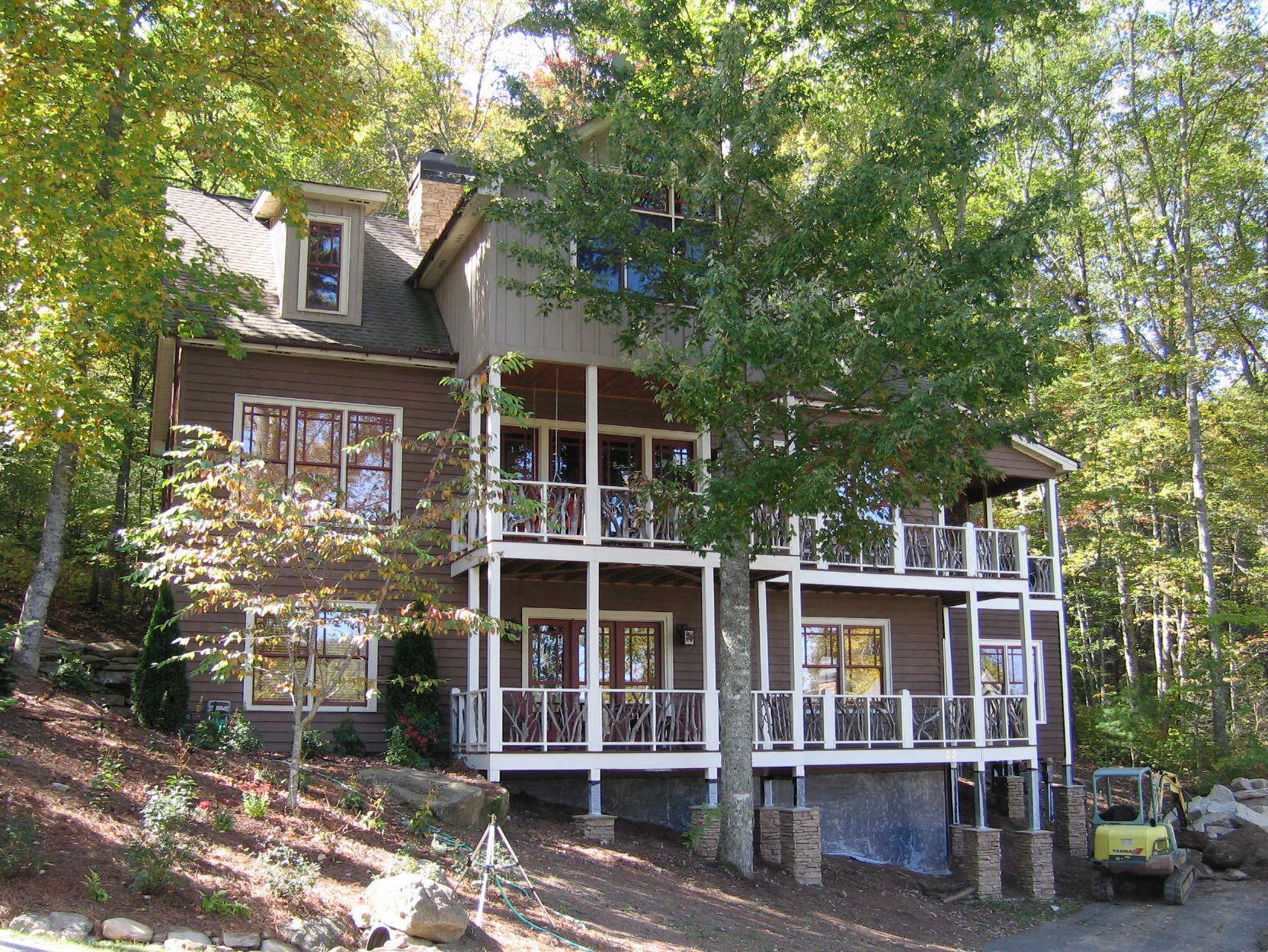 House plan exterior: Three-story home with multiple balconies, prominent dormer, and stone chimney.