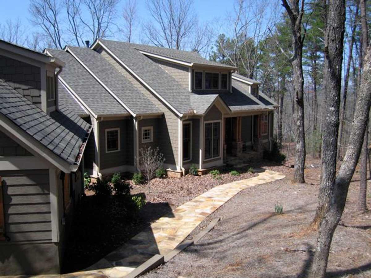 House plan exterior with multiple gables, dormer windows, and a covered front porch with stone columns.