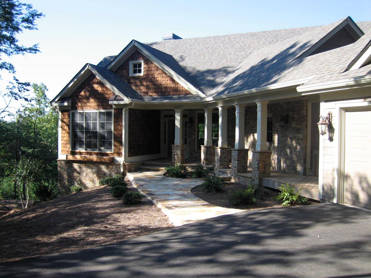 House plan exterior: One-story home with a covered porch, stone accents, shingle siding, and a prominent gable.
