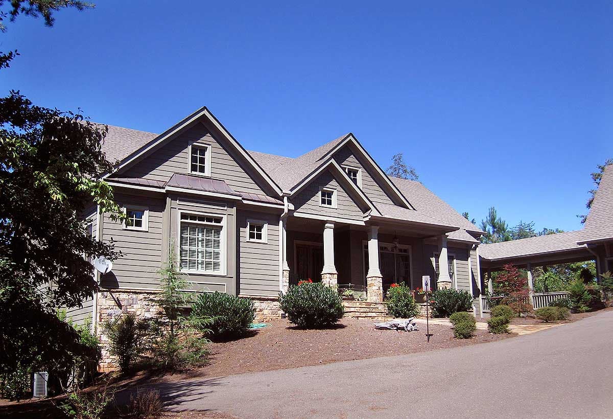House plan exterior shows a two-story home with gables, dormers, stone foundation, and covered porch supported by columns.
