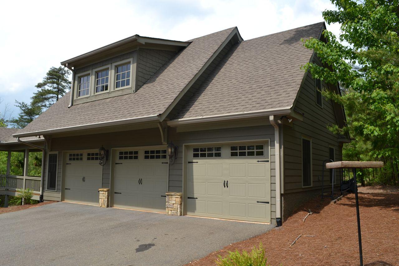 House plan exterior: three-car garage, dormer windows, shingle siding, stone accents, and gabled rooflines.