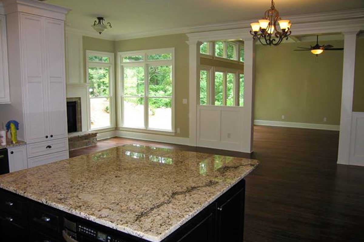 Interior view of open concept living area featuring kitchen island, fireplace, and large windows.