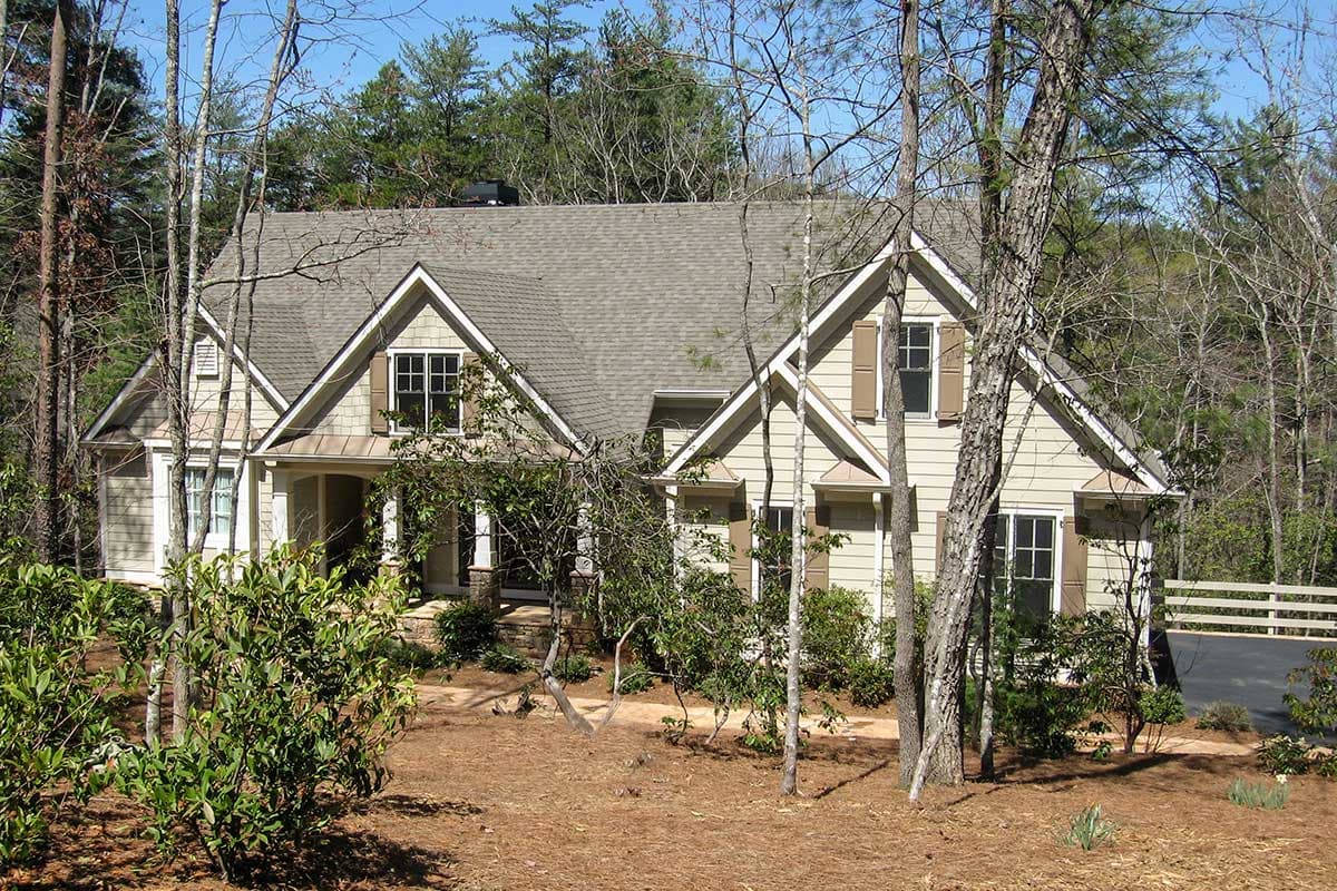 House plan exterior. Two-story Craftsman home with gabled roof, dormers, and front porch. Windows feature shutters.