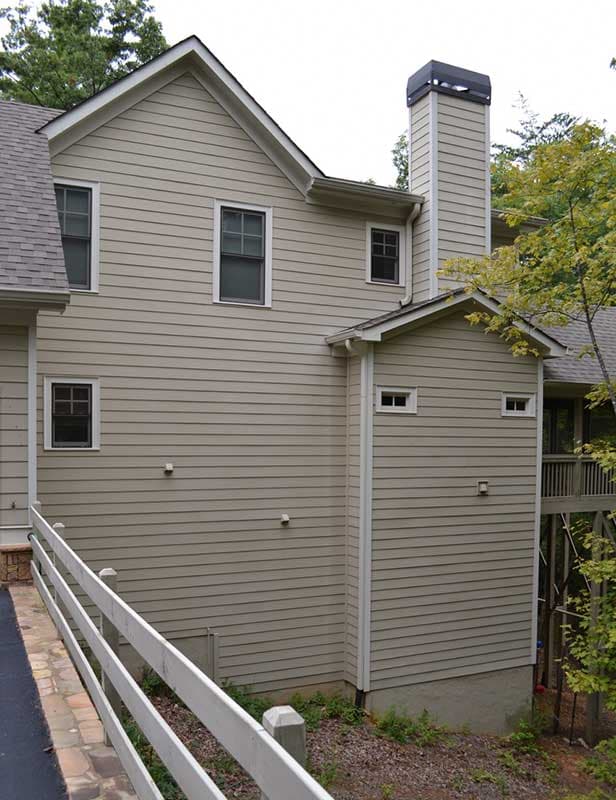 House plan exterior showing a multi-story home with horizontal siding, gables, and a prominent chimney.