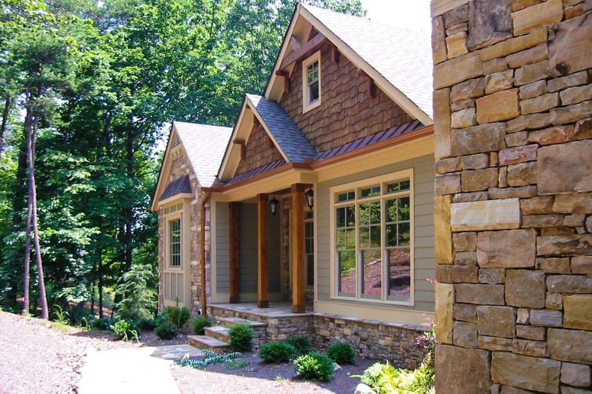 Craftsman style house plan exterior with stone facade, wood shake gables, and covered porch with timber posts.