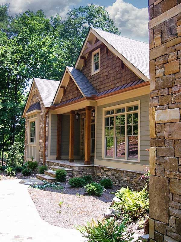 House plan exterior showing a two-story home with shingle siding, stone accents, and a covered front porch with timber columns.