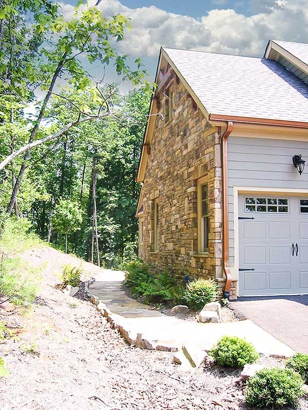 House plan exterior showing stone facade, siding, gable roof, dormers, and attached garage with carriage-style door.