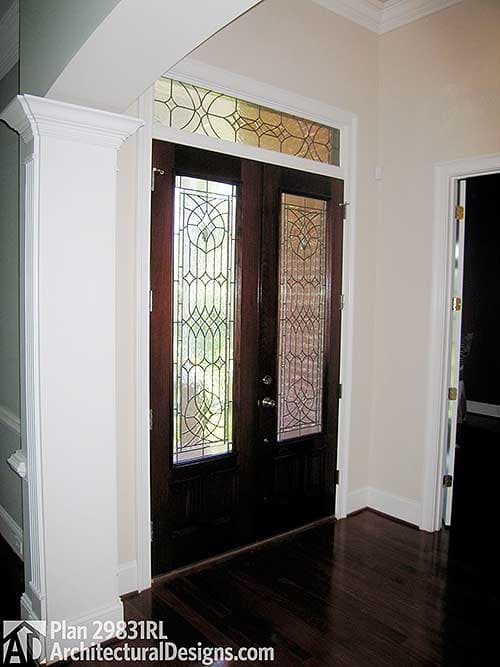 Front entry with double wooden doors, featuring decorative glass panels and transom window.