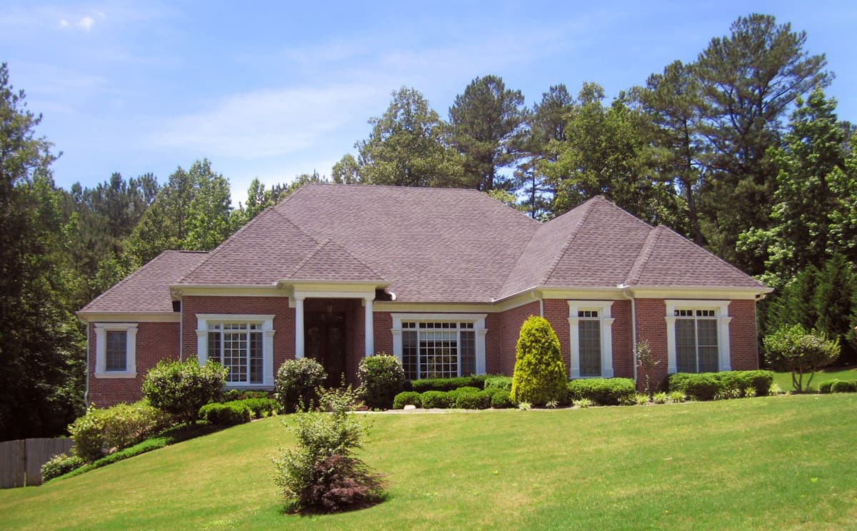 House plan exterior: One-story brick home with prominent gables, a sheltered entry porch, and numerous multi-pane windows.
