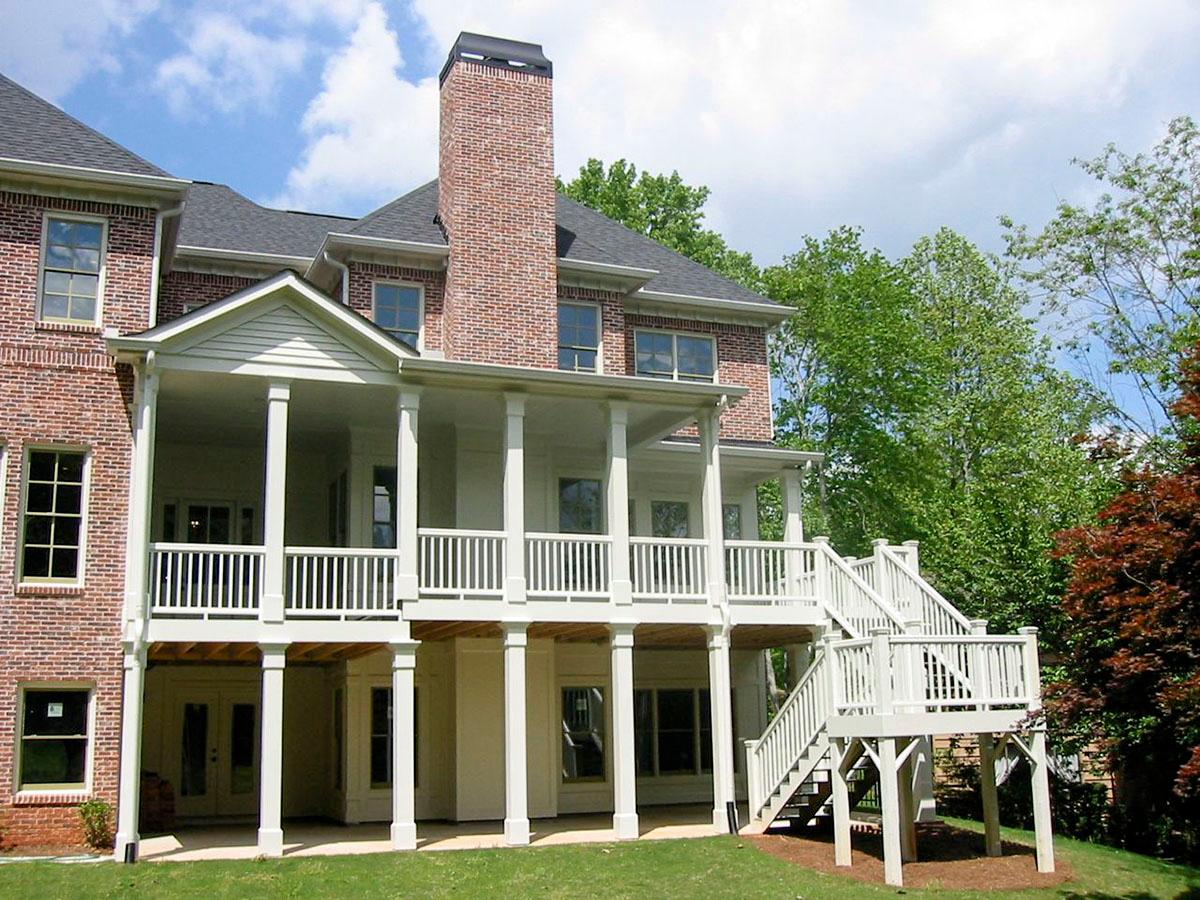 House plan exterior with brick facade, multi-level covered porches, a prominent brick chimney, and exterior stairs.