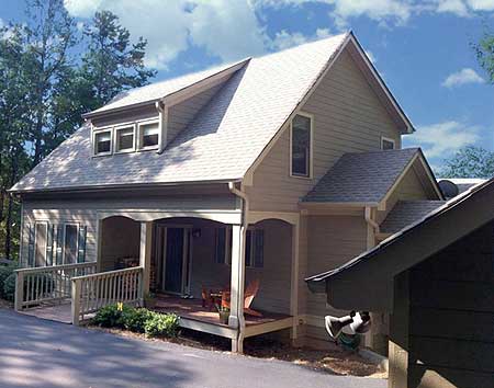 House plan exterior: Two-story home with covered porch, deck, gabled roof, and dormer windows.