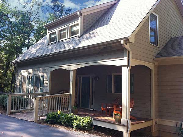 House plan exterior: Two-story home with a wraparound porch, dormer windows, and gabled rooflines.