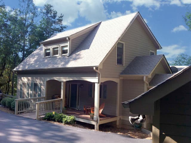 House plan exterior: Two-story home with dormers, covered front porch with arched supports, and a wheelchair ramp.