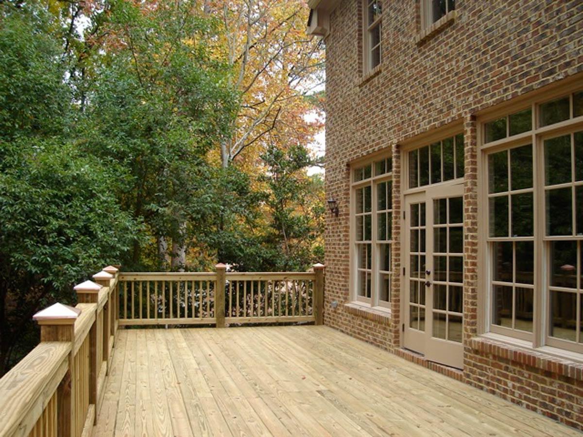 House plan exterior shows a two-story brick building with a wooden deck and french doors.