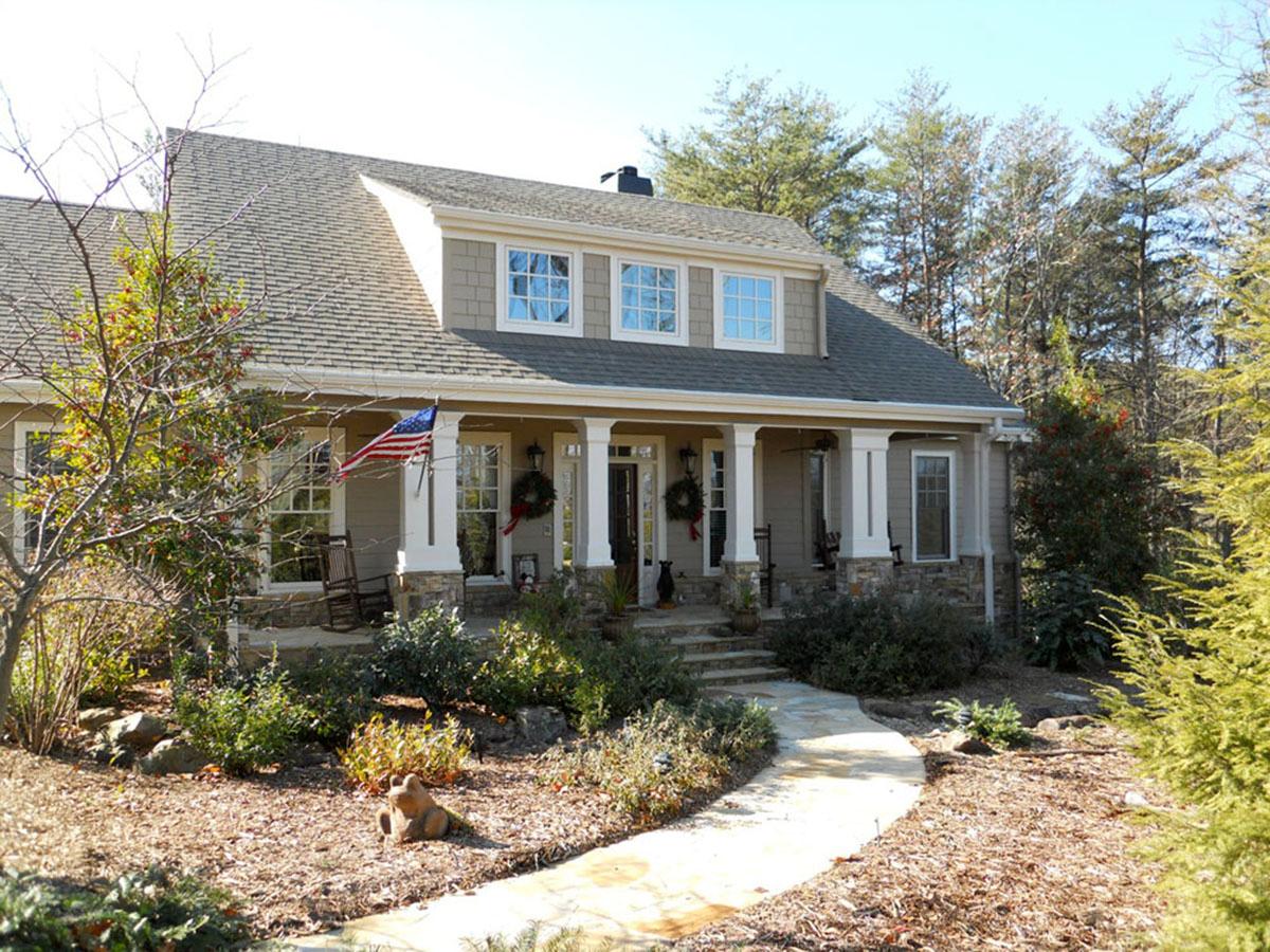 House plan exterior: Two-story home with a covered front porch, dormer windows, and stone accents.