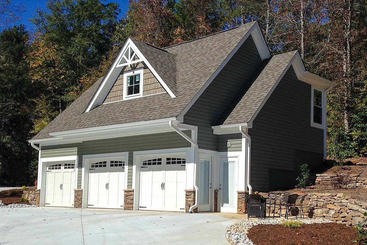 House plan exterior featuring a three-car garage with stone accents, gable dormer, and layered rooflines.
