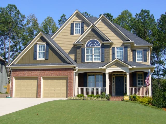 House plan exterior with gabled dormers, arched window, two-car garage, and covered front porch with columns.