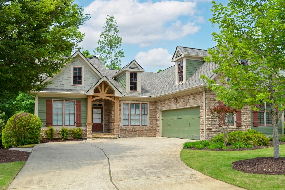 House plan exterior with Craftsman style, two stories, front-facing gables, stone veneer, and covered front porch with exposed rafters and brackets.