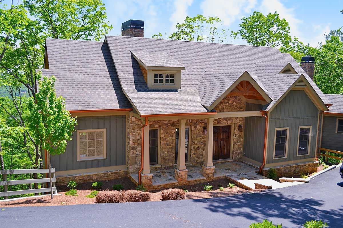 House plan exterior: Stone and board-and-batten siding, covered porch with stone columns, dormer, gable with exposed beams.
