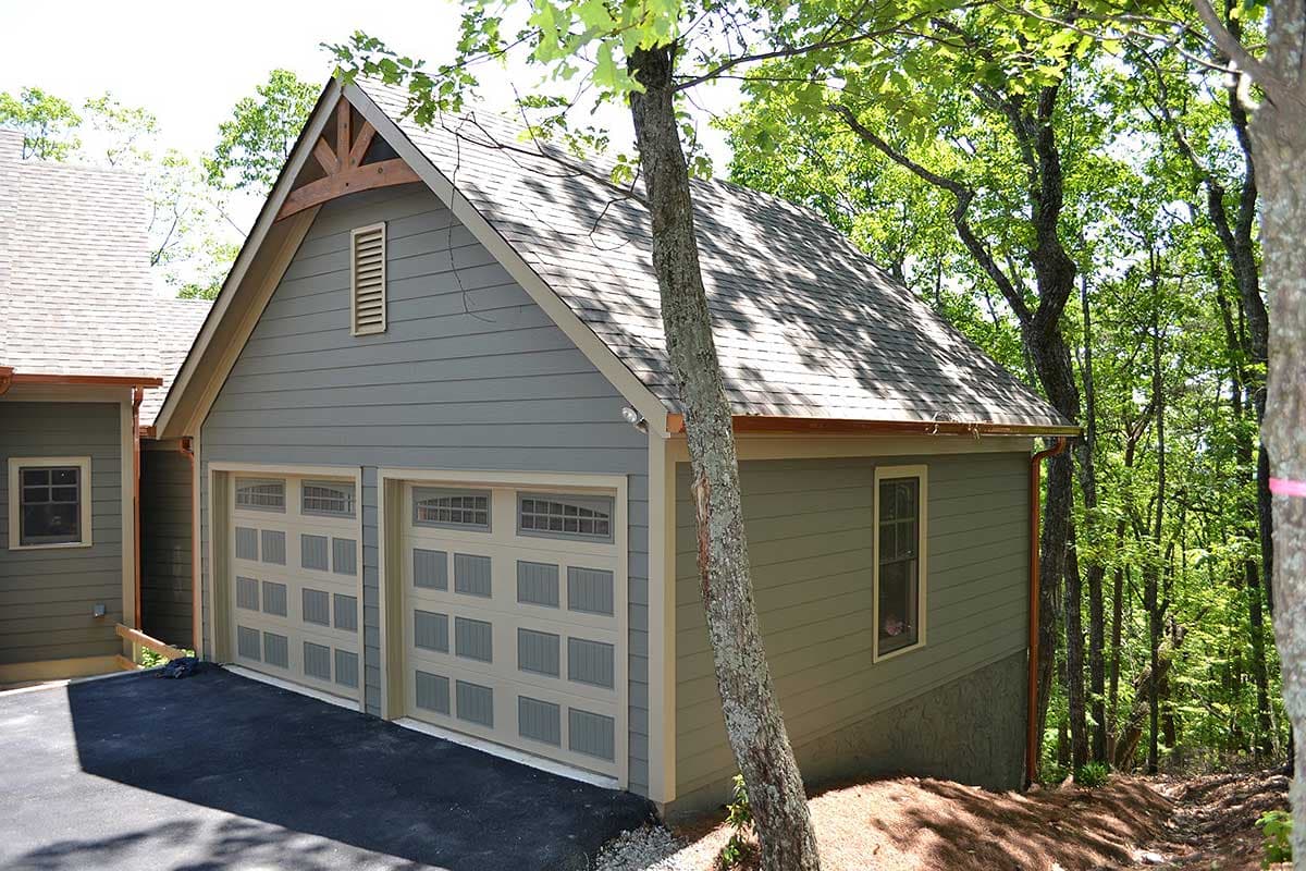 Exterior house plan showing a two-car garage with wood gable detail, siding, and windows.