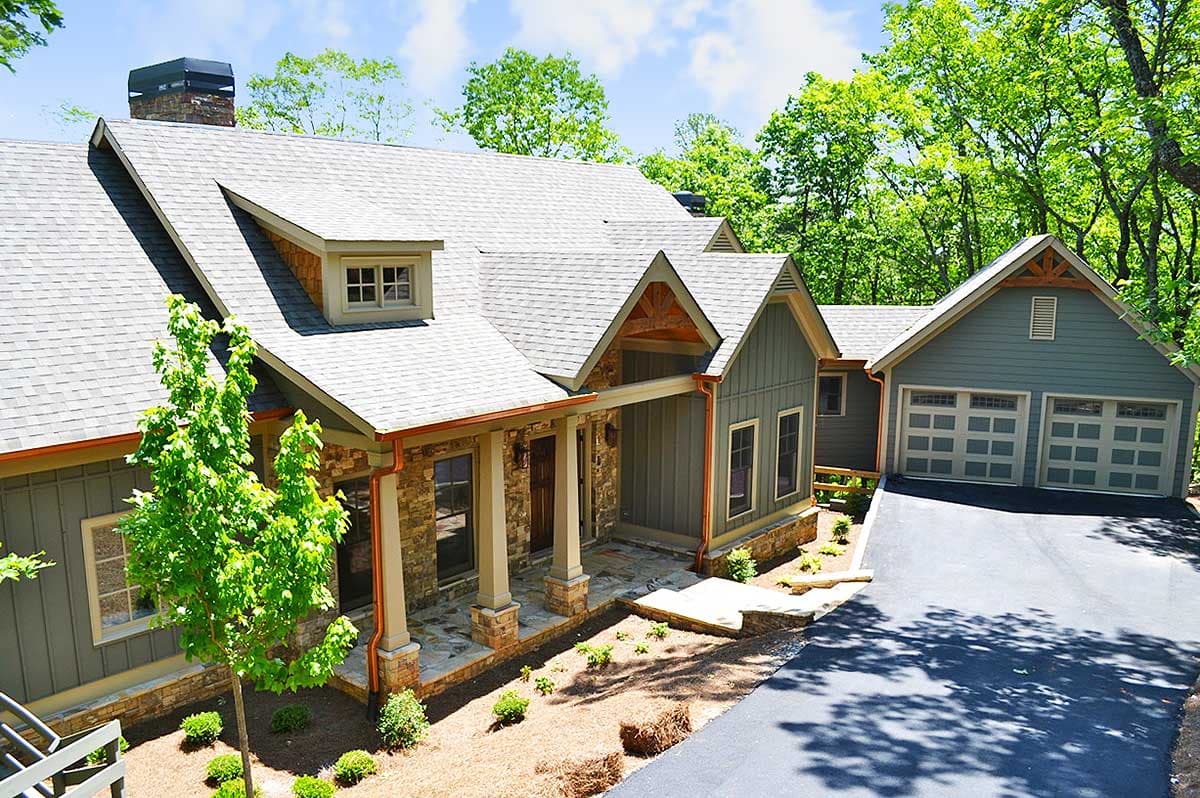 House plan exterior with stone and vertical siding, multiple gables, dormers, and a three-car garage.