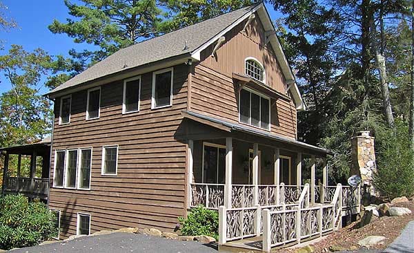Two-story house plan exterior with horizontal siding, gabled roof, covered porch with decorative railing, and stone chimney.