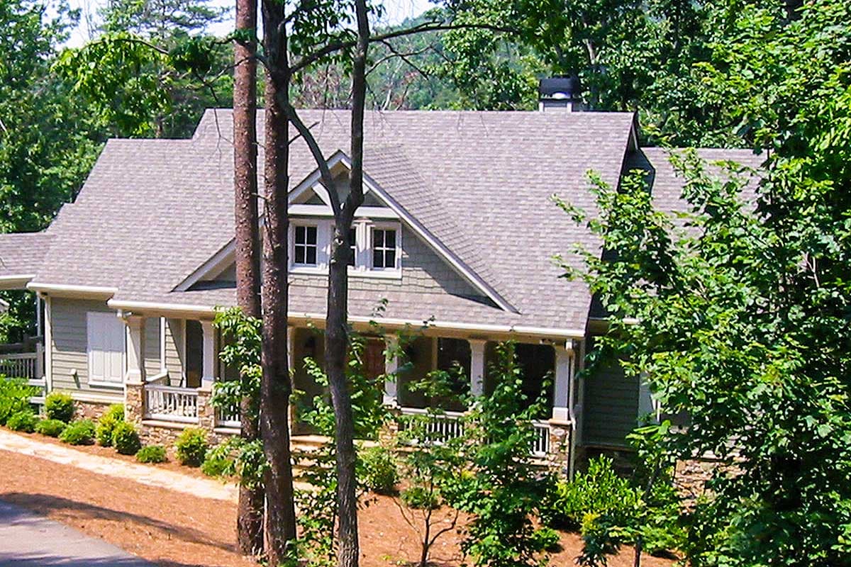 House plan exterior of a two-story home with a full-length porch, gables, and stone accents.