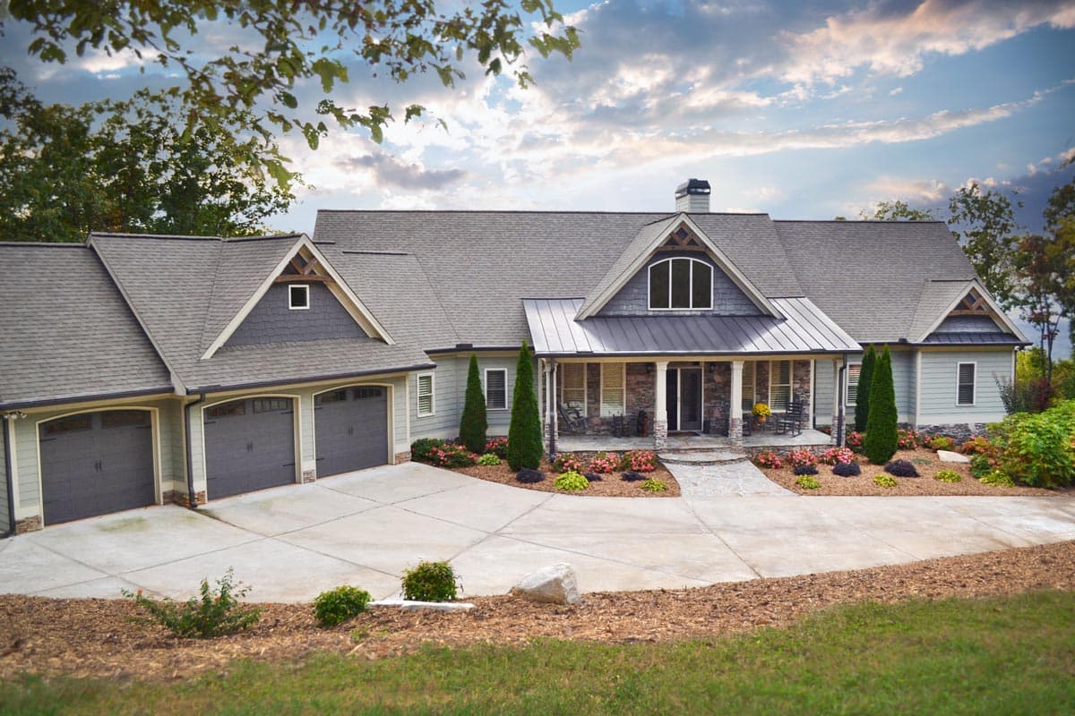 House plan exterior: Modern Farmhouse style, two stories, with a three-car garage, wraparound porch, and multiple gables.