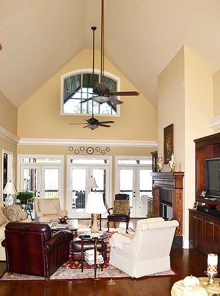 Great room with vaulted ceiling, fireplace, multiple doors to exterior, and upper arched window.