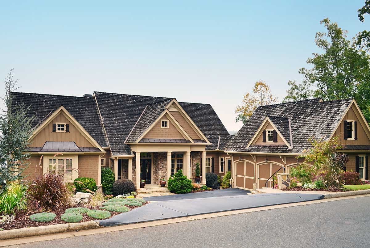 House plan exterior: Single-story home with gabled dormers, a covered front porch with stone accents, and a side-entry garage.