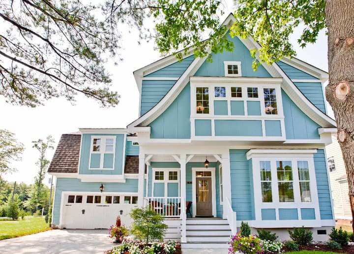 House plan exterior of a two-story blue home with a gabled front, prominent bay window, covered porch, and attached garage.
