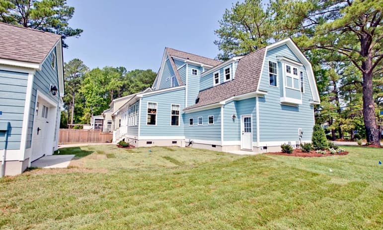House plan exterior with a gambrel roof, dormers, and attached garage. Blue siding and white trim.