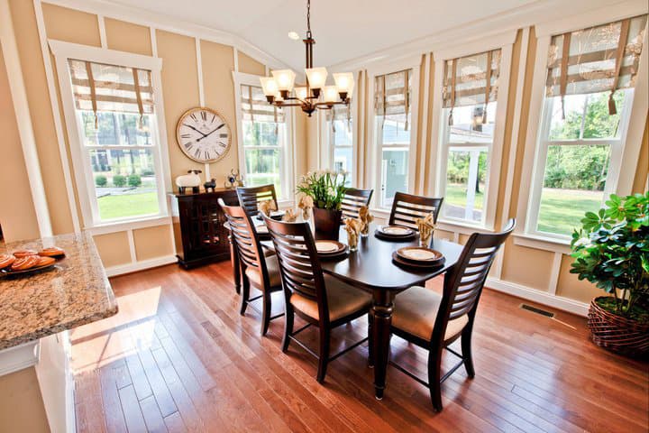 Dining room with dark wood table and chairs, large windows, and hardwood floors.