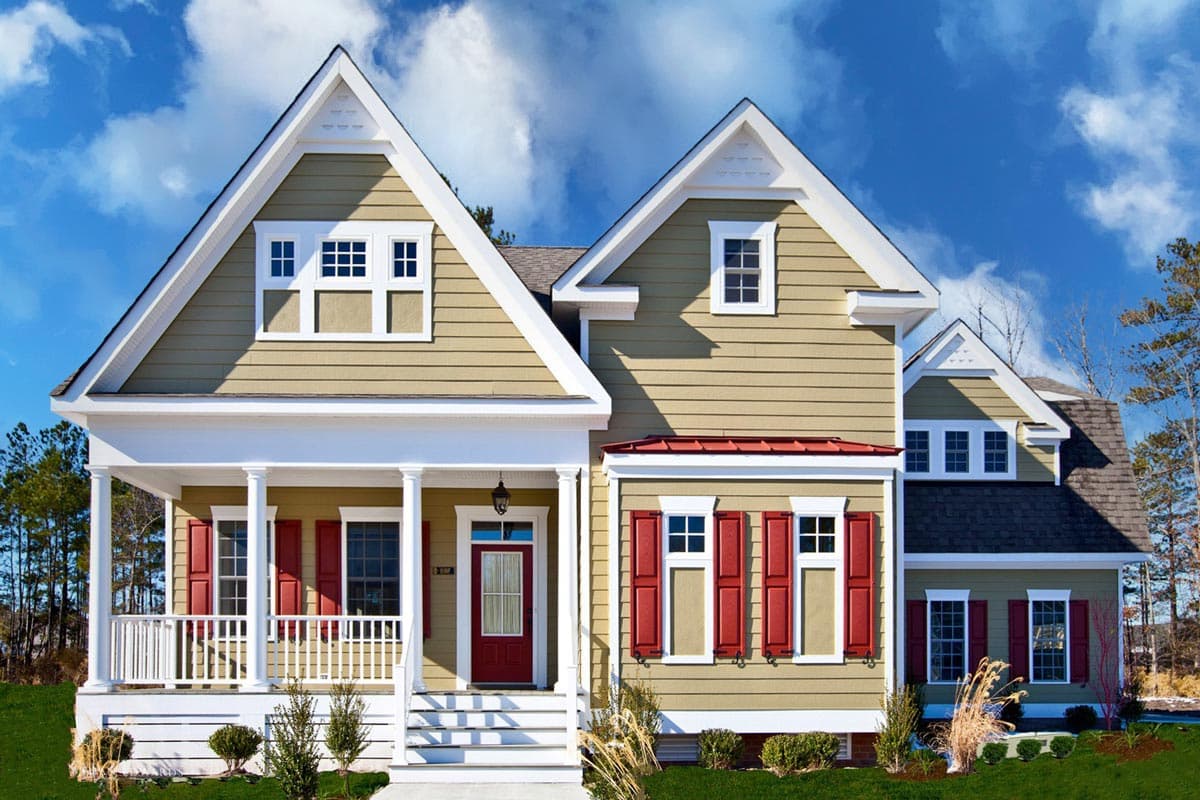 House plan exterior: Two-story home with a wraparound porch, multiple gables, dormers, and red shutters.